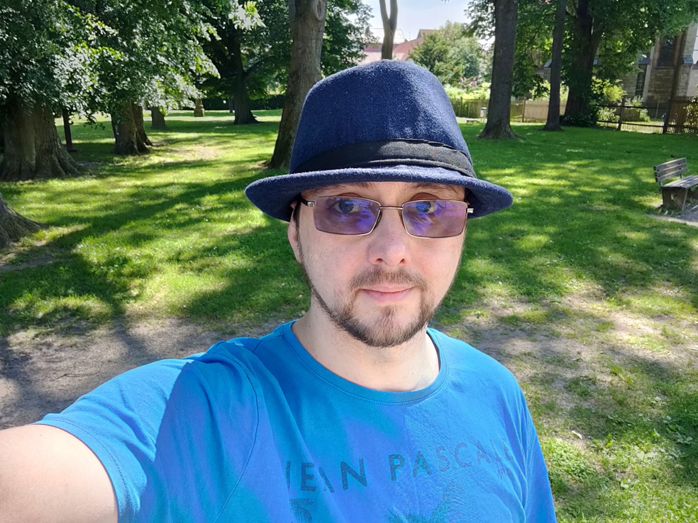 Selfie mit blauem Fedora, blauem Tshirt in einem kleinen Park.